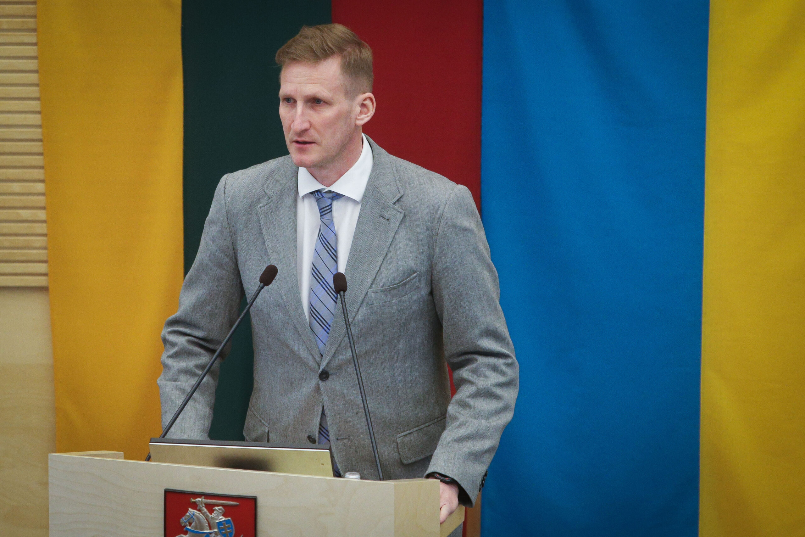 Linas Jonauskas, in front of two flags - one Lithuanian, one Ukrainian - standing before a podium