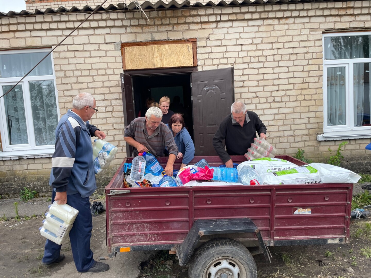 Sadovo gyventojai padėjo iškrauti atvežtą paramą, bet kartu baiminosi apšaudymo – išvakarėse atlėkusi bomba išvertė mokyklos tvorą. E. BUTRIMO nuotr. 