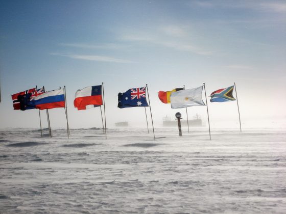 Pasaulio kraštas Formalųjį ašigalį puslankiu supa dvylikos valstybių, 1959 m. pasirašiusių Antarktidos sutartį, vėliavos.