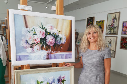 Panevėžietė Raimonda Narkevičienė – diplomuota inžinierė, besirūpinanti kelių priežiūra ir statyba. Pasibaigus darbo dienai, ji brėžinius iškeičia į teptukus ir spalvas. Raimonda atvirauja, kad jaunystėje primirštą pomėgį piešti atradusi ne taip seniai, kai netikėtai pravėrė suaugusiesiems skirtos dailės studijos duris. Nors panevėžietė sako teptuką paėmusi norėdama pabėgti nuo rutinos ir pravėdinti galvą, jos kūrybą įvertino ir garsiausios Jungtinių Amerikos Valstijų galerijos ir muziejai – panevėžietė prestižiniame tapybos konkurse „American Art Awards“ laimėjo pirmąją vietą su darbu „Bijūnai vazoje“.