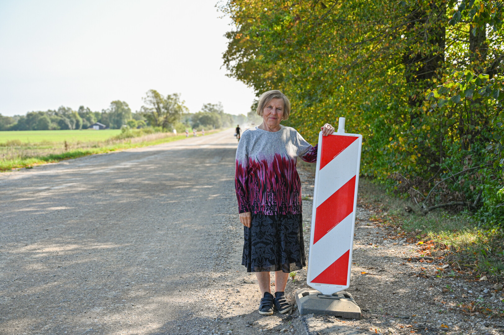 Tarp Ramygalos ir Vadoklių gyvenanti Angelė Kielienė nesupranta, kodėl reikėjo gremžti dar gerą pro jos namus einančio kelio asfaltą ir lieti naują. P. ŽIDONIO nuotr.