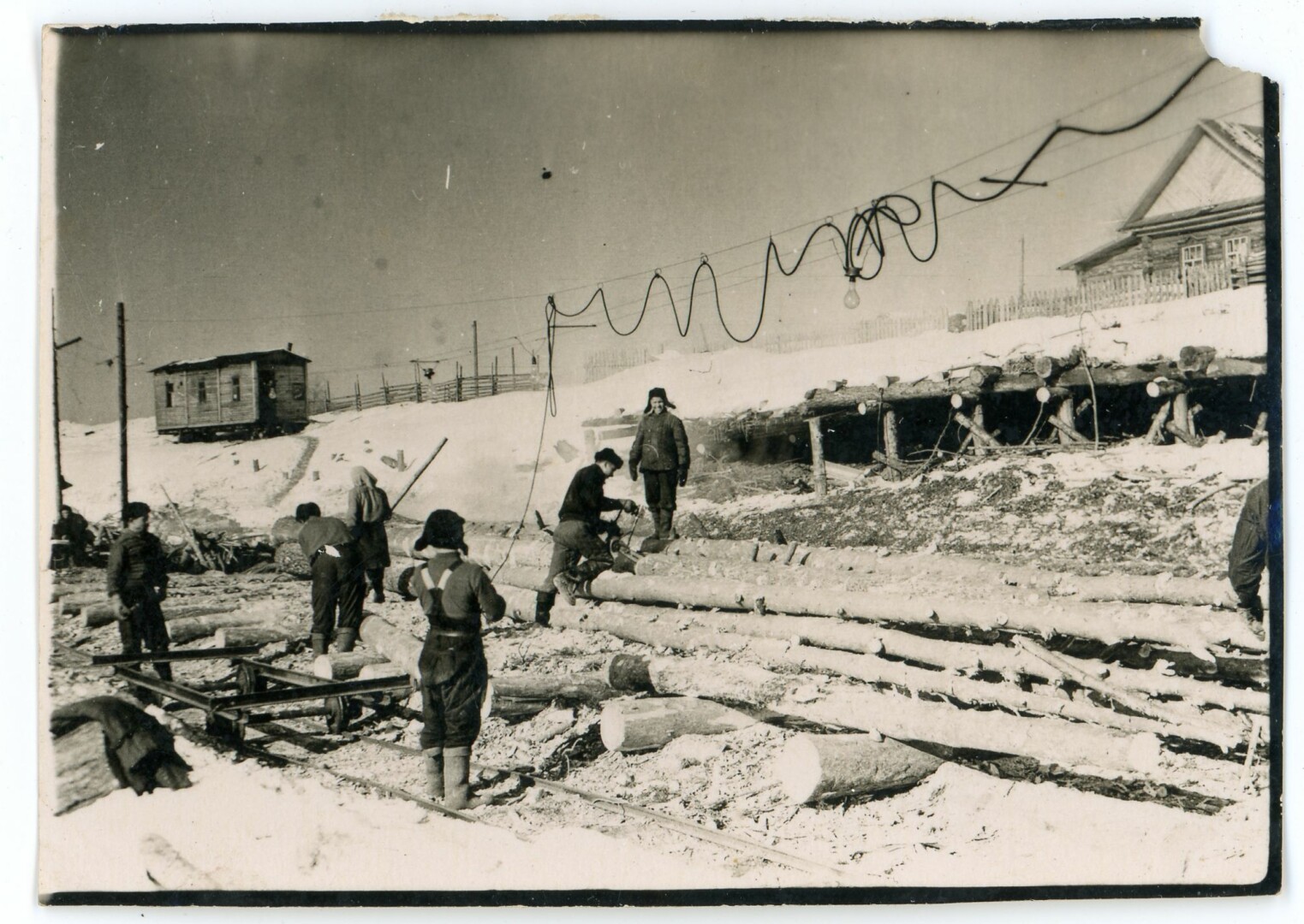 Tremtiniai ruošia rąstus išgabenimui. Antrame plane, kairėje stovi vagonėlis, kuriame buvo galandami darbo įrankiai. Apie 1956 m. S. POBEDINSKO nuotr. 