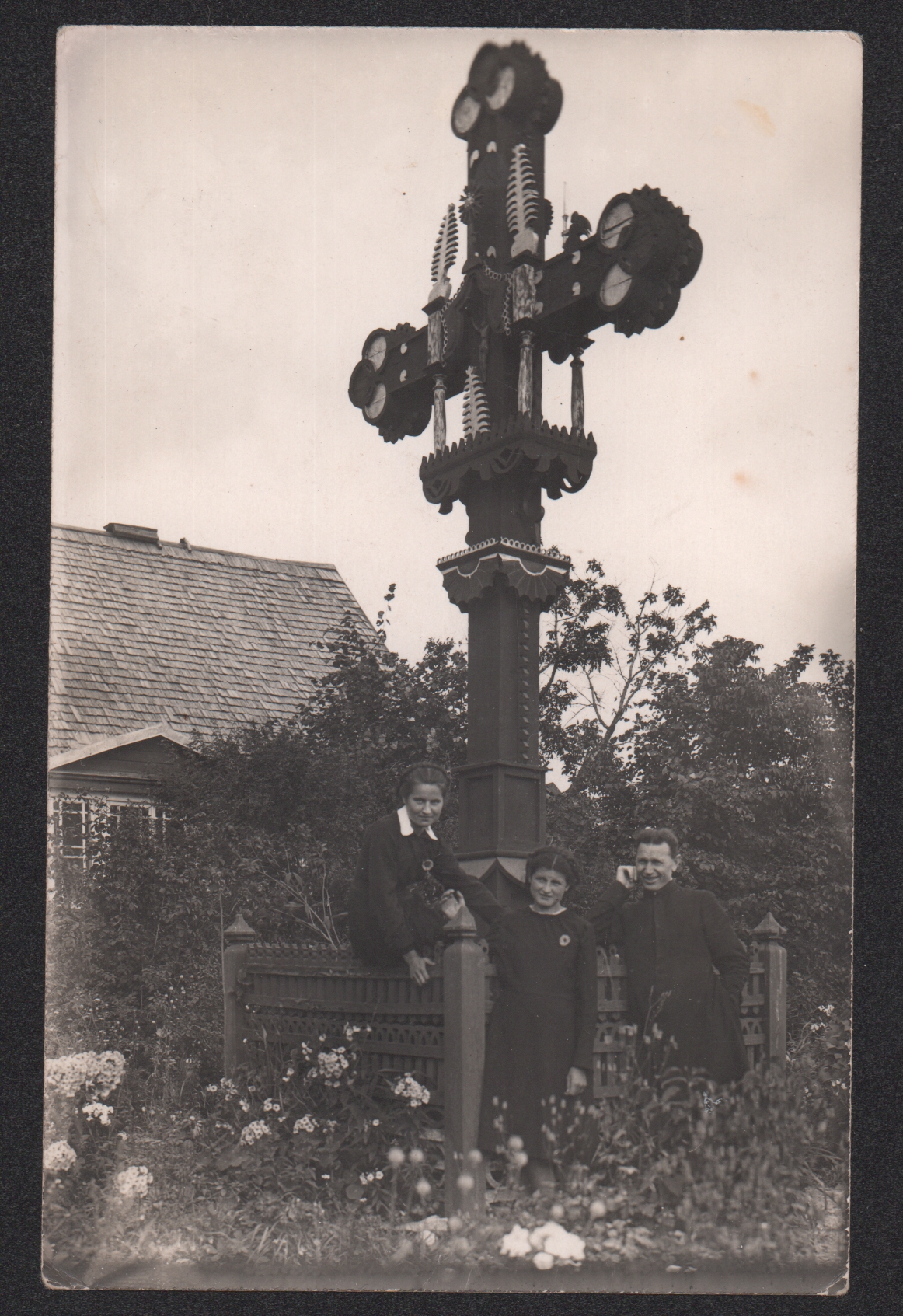 Aleksandravėlės Šv. Pranciškaus Sarafiškojo parapijos klebonas Antanas Misevičius ir dvi jaunos moterys prie puošnaus kryžiaus Aleksandravėlės klebonijos darželyje apie 1941 m. Šį kryžių 1928 m. minint Lietuvos nepriklausomybės dešimtmetį pastatė šauliai. Vėliau iš klebonijos kiemo jis perkeltas į bažnyčios šventorių, galiausiai blogėjant būklei – į pačią bažnyčią.