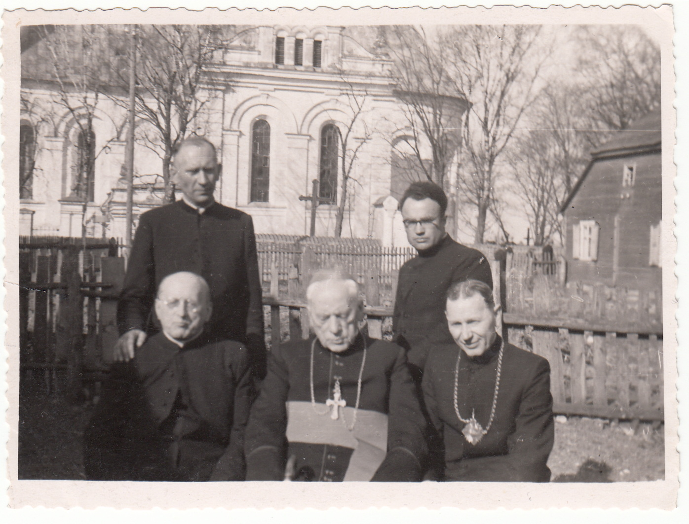 Arkivyskupas Teofilius Matulionis (sėdi centre) su grupele dvasininkų Šeduvos Švč. Kryžiaus Atradimo bažnyčios fone. Grįžęs iš įkalinimo sovietų kalėjimuose ir išvarytas iš savo vyskupijos, nuo 1958 m. jis gyveno Šeduvoje. Fotografuota 1962 m. pavasarį. Tai viena iš paskutiniųjų arkivyskupo T. Matulionio nuotraukų – 1962 m. rugpjūčio 20 d. jis mirė po bute sovietų saugumo atliktos kratos ir nenustatytų vaistų injekcijos. Nuotraukos kairėje sėdi Šeduvos parapijos altarista Augustinas Pronskietis, dešinėje – Šeduvos parapijos klebonas kanauninkas Antanas Misevičius, dešinėje stovi Šeduvos vikaras Jonas Juodelis, vėliau ilgametis Panevėžio Šv. apaštalų Petro ir Povilo parapijos klebonas.